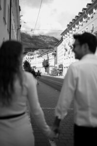 Black-and-white photo of a blurred couple walking through Innsbruck with focus on the city
