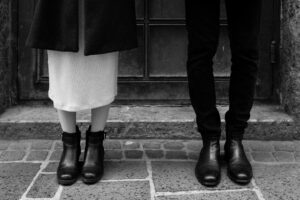 Black-and-white close-up of a couple’s legs and feet with dress and suit trousers