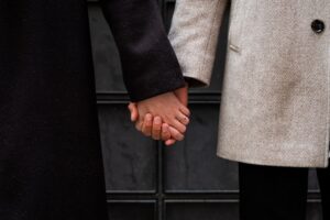 Close-up of hands holding each other in front of an old door