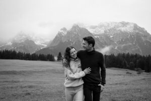 Man embracing his girlfriend while both laugh in front of snowy mountains