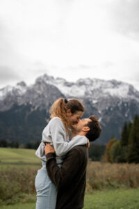 Man lifting his fiancée by the waist while she smiles at him