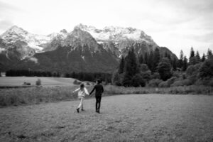Young couple walking toward a lake with snowy mountains in the background and motion blur in black and white