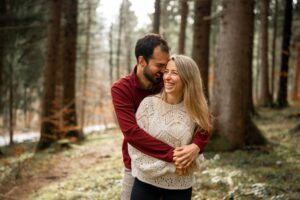 Man embracing his partner from behind while both cross their hands in front of their bodies