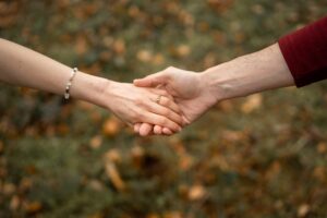Close-up of hands with focus on the engagement ring and autumn leaves in the background