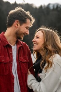 Medium close-up photo of a young couple walking in front of a forest