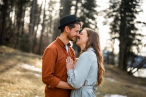 Young couple standing in golden light before a forest while almost kissing