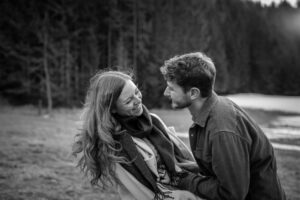 Cinematic black-and-white photo of a young couple laughing together in a field