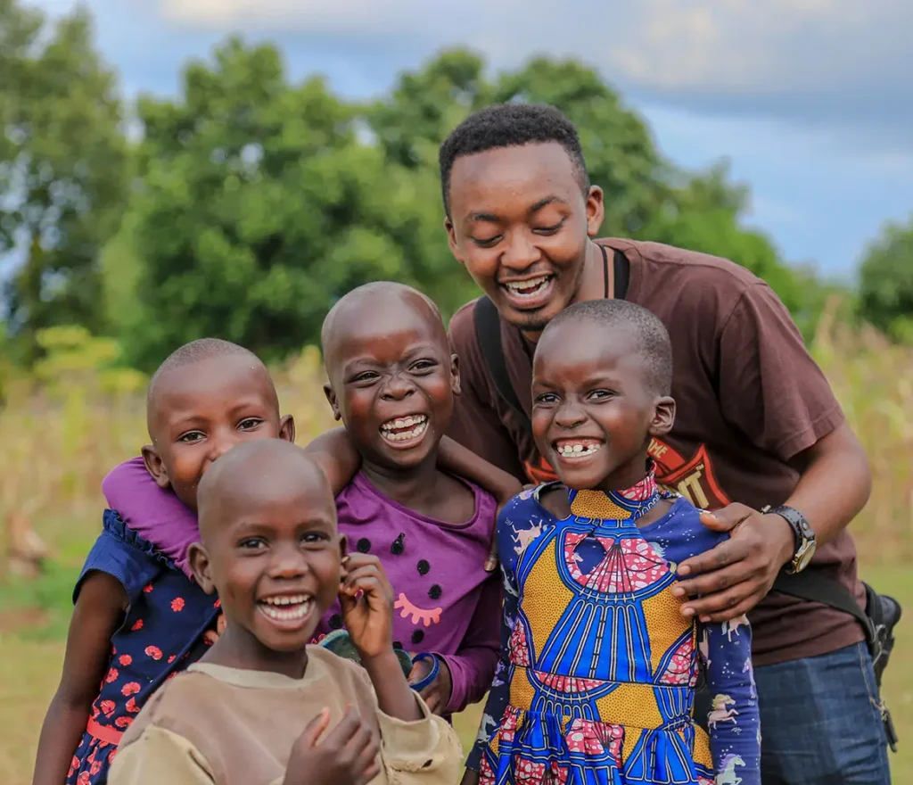 Young African man laughing together with four children in Uganda